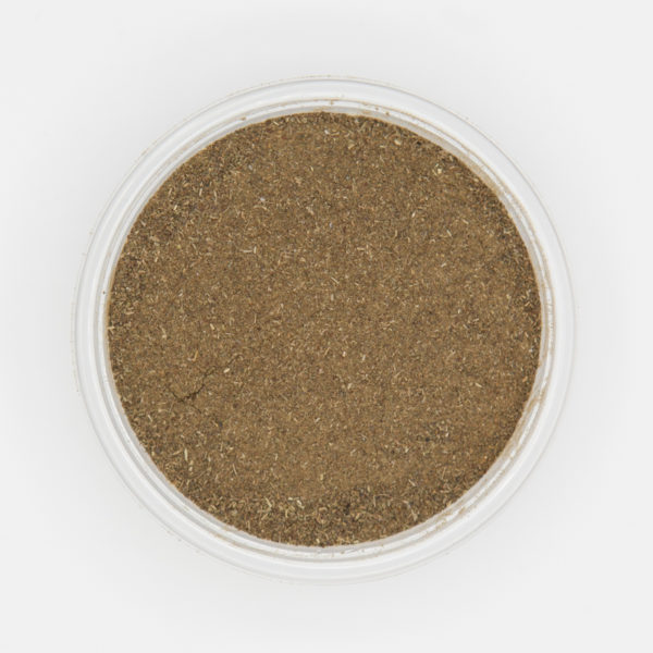 Dried ground basil herb spice in a circular dish on a white background