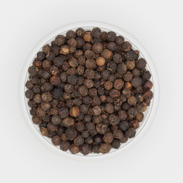 Whole Black Peppercorns Up Close In Small Dish On White Background